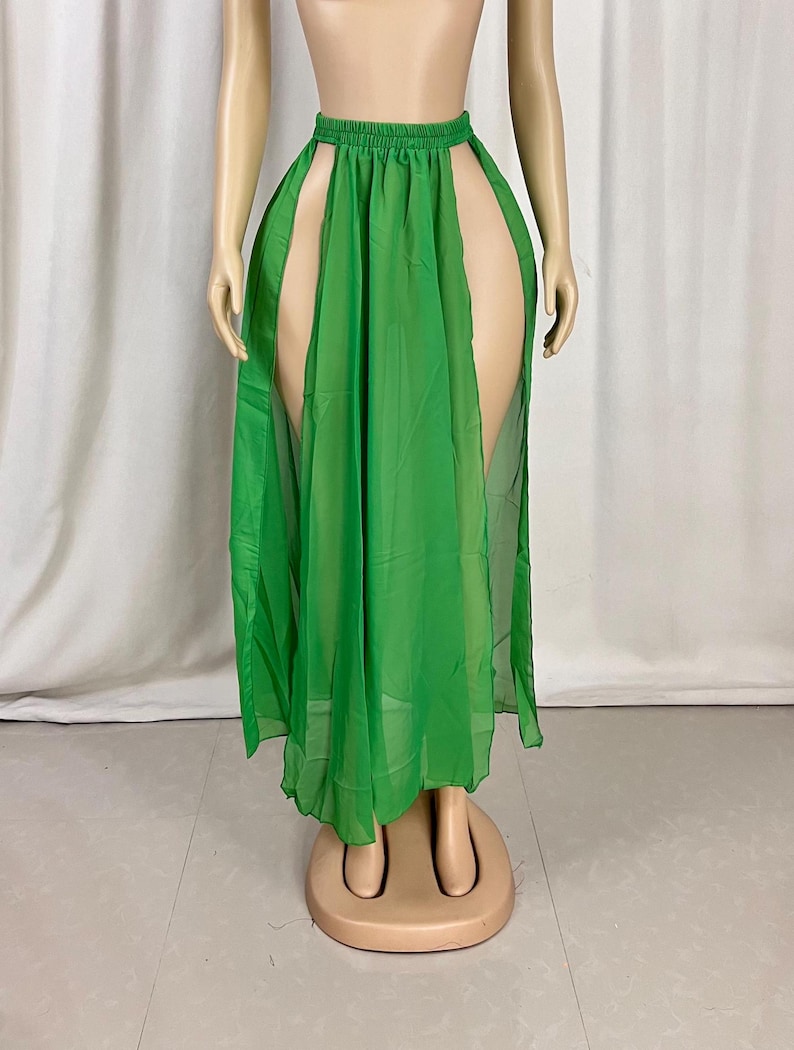 Puede incluir: Una falda larga de gasa verde con dos aberturas altas a los lados. La falda est&aacute; fruncida en la cintura y tiene un dise&ntilde;o sencillo.