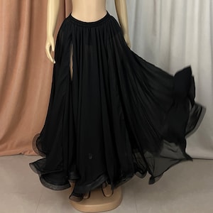 May include: A black chiffon skirt with a high waist and a slit in the front. The skirt is flowing and has a ruffled hem.
