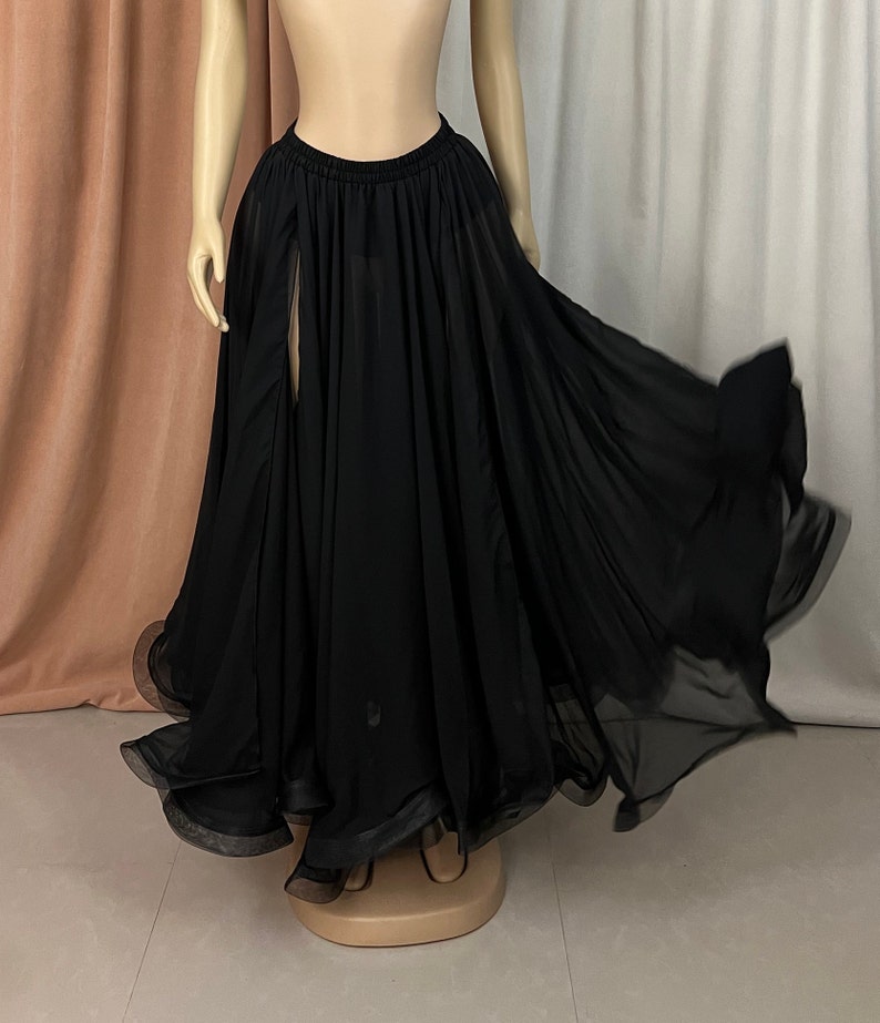 May include: A black chiffon skirt with a high waist and a slit in the front. The skirt is flowing and has a ruffled hem.