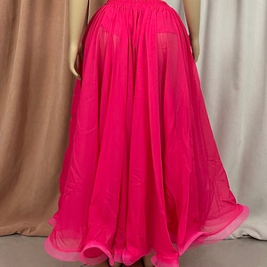 May include: A bright pink sheer skirt with a gathered waistband. The skirt is flowing and has a ruffled hem.