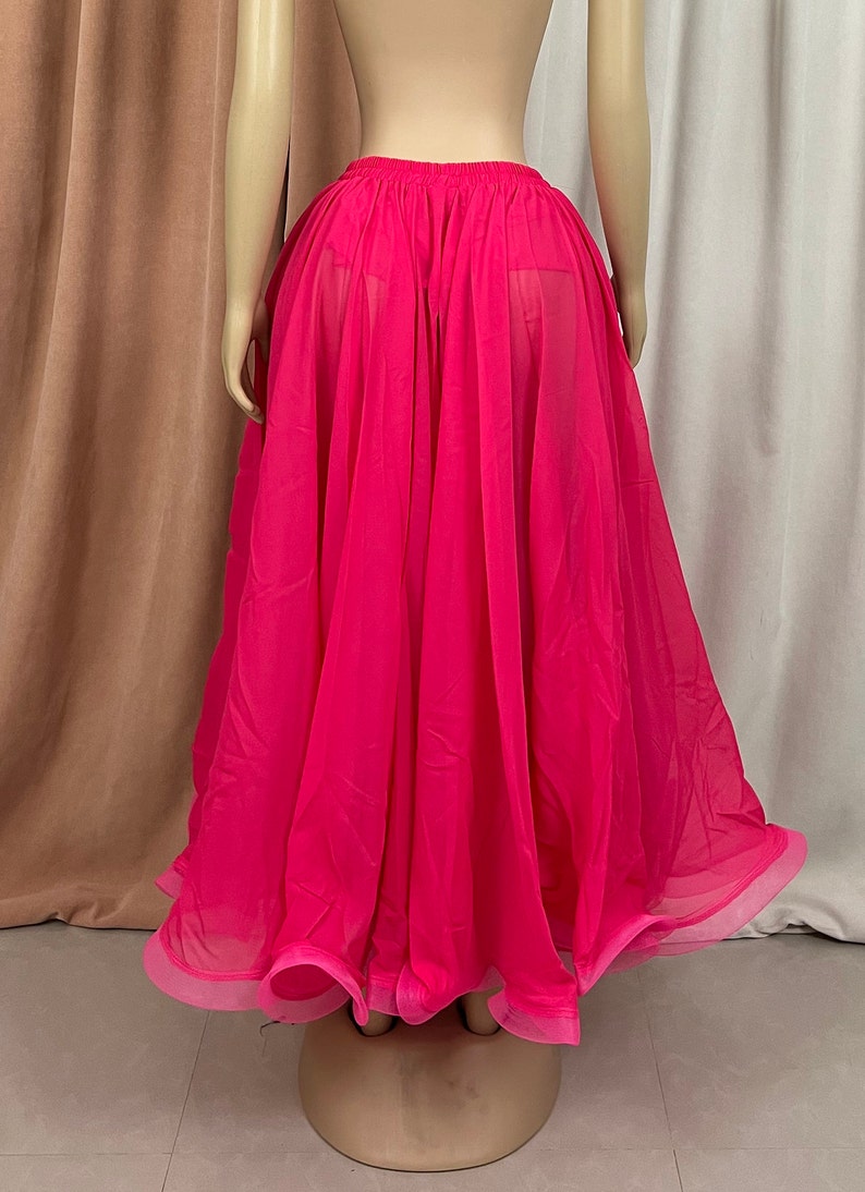 May include: A bright pink sheer skirt with a gathered waistband. The skirt is flowing and has a ruffled hem.