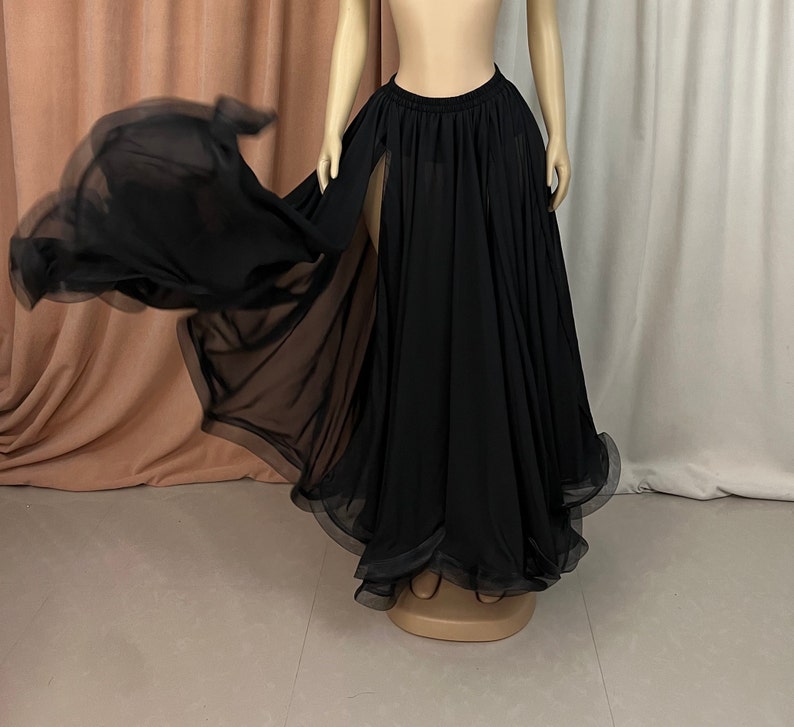 May include: A black sheer maxi skirt with a high waist and a front slit. The skirt is flowing and has a ruffled hem.