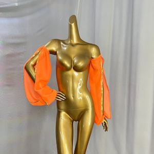 May include: A pair of bright orange sheer sleeves with gold trim. The sleeves are off the shoulder and have a gathered look at the elbow.