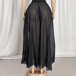 Puede incluir: Una falda maxi negra transparente con una silueta fluida de l&iacute;nea A. La falda est&aacute; hecha de una tela ligera y semitransparente.