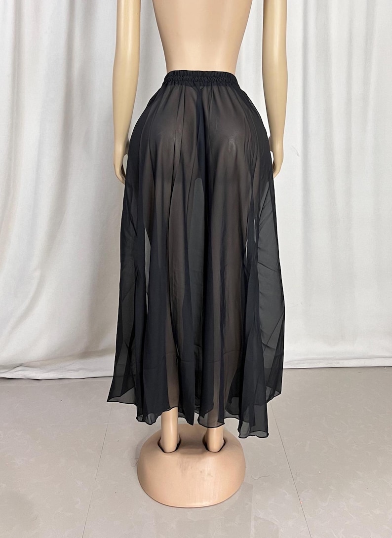 Puede incluir: Una falda maxi negra transparente con una silueta fluida de l&iacute;nea A. La falda est&aacute; hecha de una tela ligera y semitransparente.