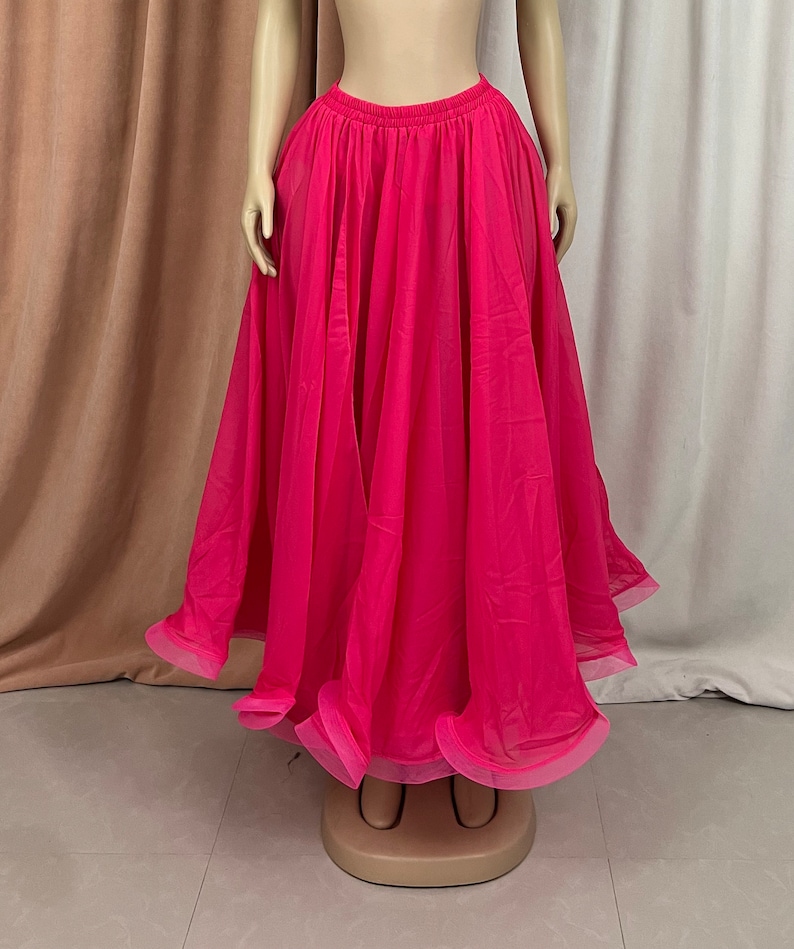 May include: A bright pink, flowing chiffon skirt with a gathered waistband. The skirt is long and full, with a layered design.