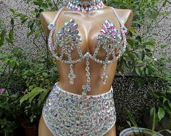 Pode incluir: Um biquíni branco de cintura alta e um top de biquíni combinando com strass iridescentes. O conjunto inclui um colar de strass combinando.