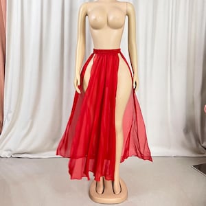 Puede incluir: Una falda maxi roja de gasa con una abertura alta a cada lado. La falda est&aacute; hecha de una tela ligera y tiene una silueta fluida.