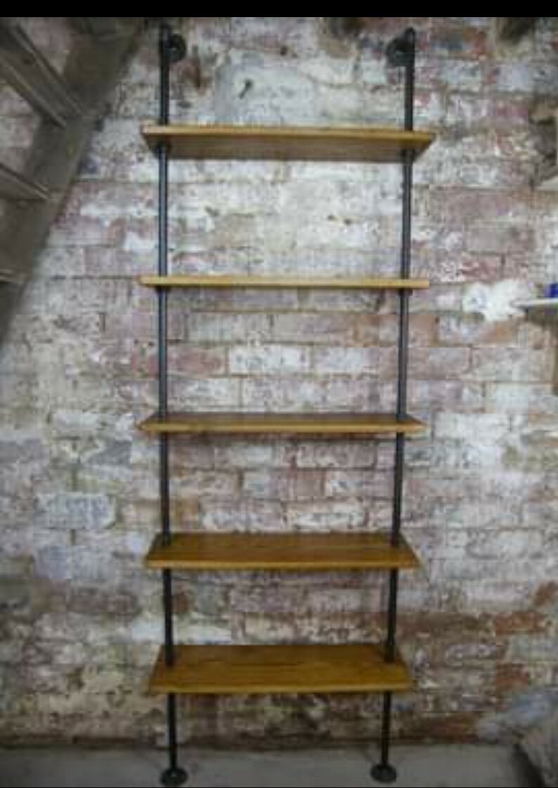 May include: A black metal pipe shelving unit with five wooden shelves. The shelves are mounted to a brick wall.