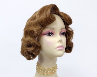 Könnte beinhalten: Eine braune Perücke mit kurzen, gewellten Locken, die zu einem Vintage-Bob aus den 1920er Jahren gestylt sind. Die Perücke sitzt auf einem Mannequin-Kopf mit einer goldenen Perlenkette.