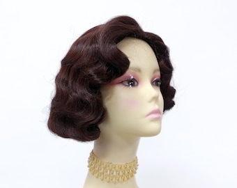 May include: A brown wig with short, curled waves styled in a vintage bob. The wig is on a mannequin head with a gold beaded choker.