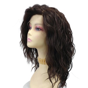 Peut inclure: Une perruque synthétique ondulée brune sur une tête de mannequin. La perruque a une dentelle frontale et est coiffée en une coupe dégradée mi-longue.