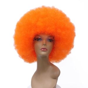 Puede incluir: Una peluca afro de color naranja brillante en una cabeza de maniquí. La peluca es muy grande y esponjosa.