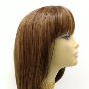 May include: A long, straight brown wig with light brown highlights and a fringe. The wig is styled with a side parting and the ends are slightly curled under.