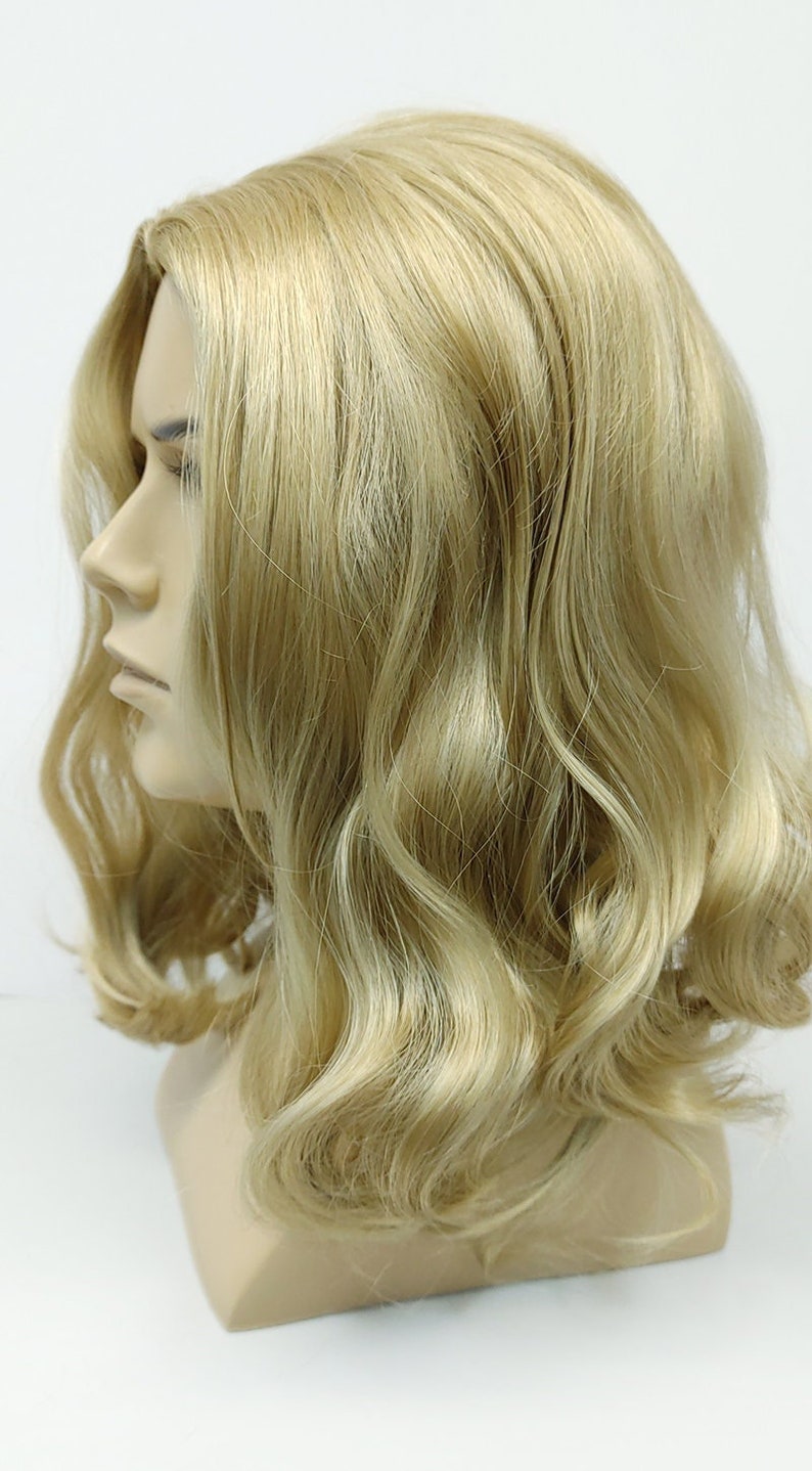 Peut inclure: Une perruque blonde avec des cheveux ondul&eacute;s coiff&eacute;s en un bob mi-long.