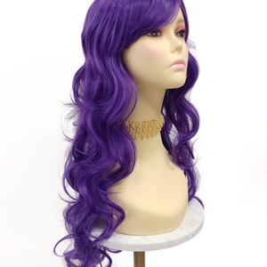 May include: A long, wavy purple wig with side-swept bangs. The wig is styled in loose curls and is worn on a mannequin head.