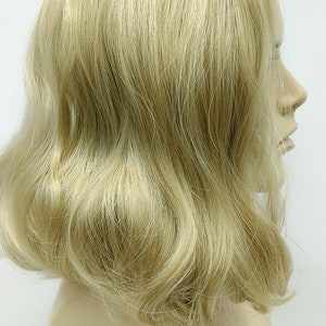 Peut inclure: Une perruque blonde avec un style ondul&eacute;. La perruque est sur une t&ecirc;te de mannequin.