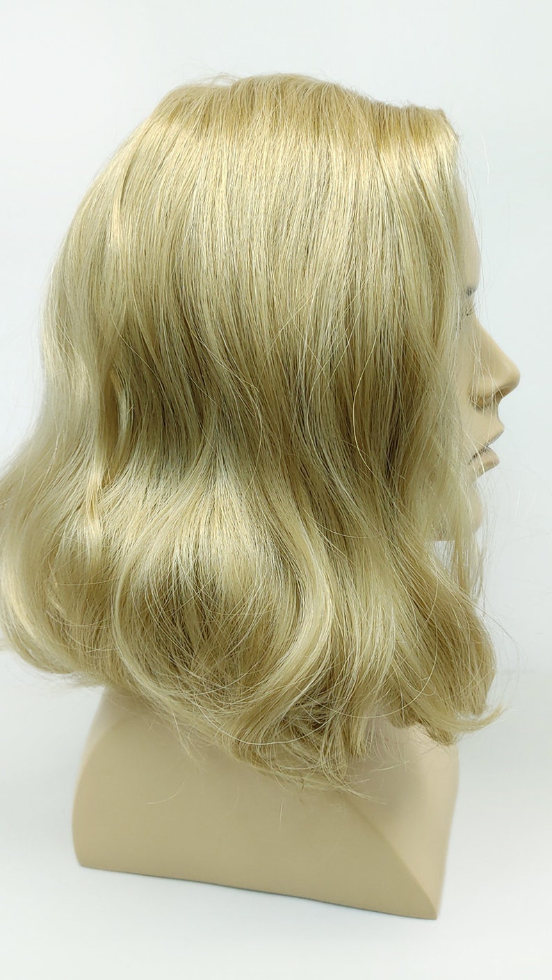 Peut inclure: Une perruque blonde avec un style ondul&eacute;. La perruque est sur une t&ecirc;te de mannequin.