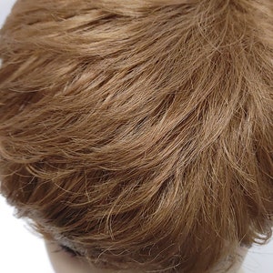 Short tapered pixie cut in strawberry blonde wig with tapered sides and face-framing layers