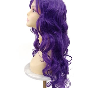 May include: A long, wavy purple wig with bangs. The wig is styled in loose curls and is displayed on a mannequin head.