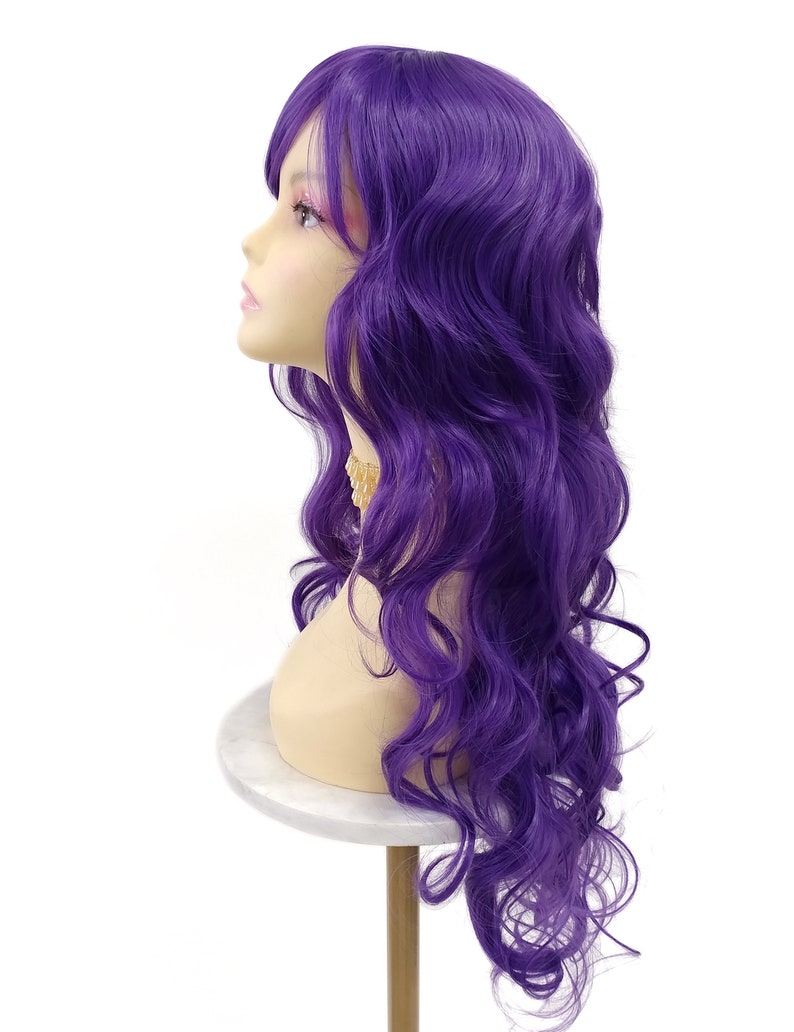 May include: A long, wavy purple wig with bangs. The wig is styled in loose curls and is displayed on a mannequin head.