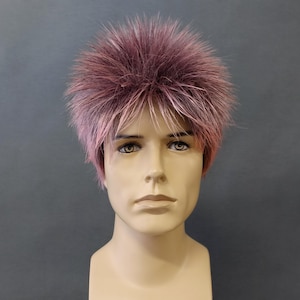 May include: A mannequin head with a spiky, short wig. The wig features a blend of pink and light blonde colors, creating a textured, layered effect. The mannequin has a neutral expression and is set against a plain background.