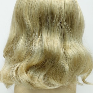 Peut inclure: Une perruque blonde avec un style ondul&eacute;. La perruque est sur une t&ecirc;te de mannequin.