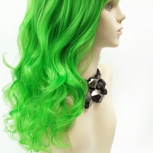 May include: A bright green wig with long, wavy hair. The wig is styled with a side part and bangs.
