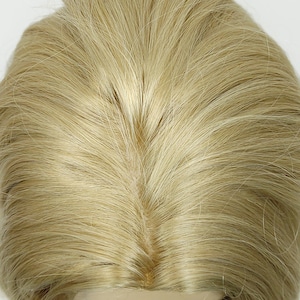 Peut inclure: Une perruque blonde clair avec un style droit et lisse. La perruque est sur une t&ecirc;te de mannequin et le dessus de la perruque est visible.