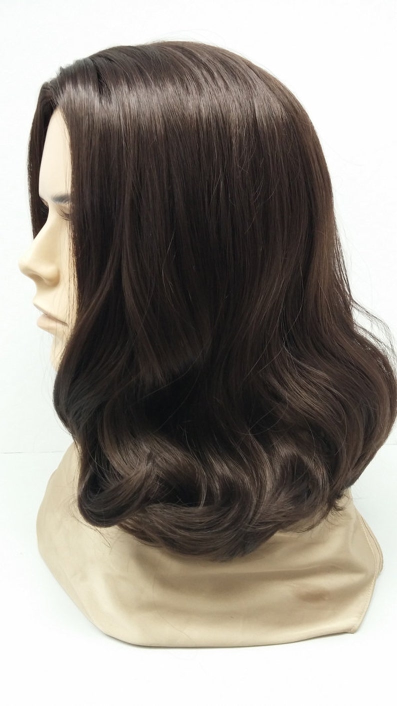 May include: A dark brown wig with shoulder-length, wavy hair. The wig is styled with a side part and features soft curls. The wig is displayed on a mannequin head against a white background. The wig's color is a rich, dark brown.