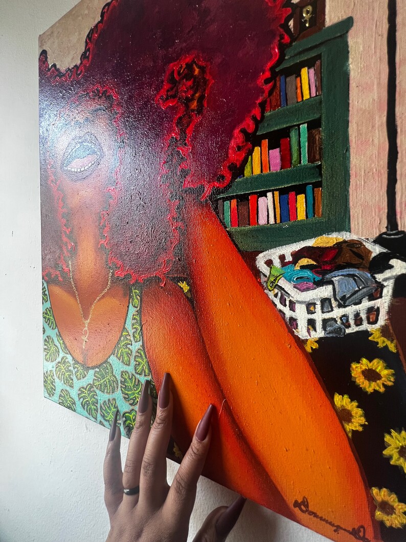 May include: A painting of a woman with a large, red afro. She is wearing a green and blue tank top with a floral pattern. The painting is set in a room with a bookshelf and a basket of clothes.