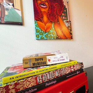 May include: A stack of four books with colorful covers. The top book is titled "A Day Late and a Dollar Short" by Terry McMillan. The second book is titled "An Introduction to Painting Flowers" by Elisabeth Harden. The third book is titled "Kehinde Wiley" and the fourth book is titled "Somaya Critchlow Paintings".