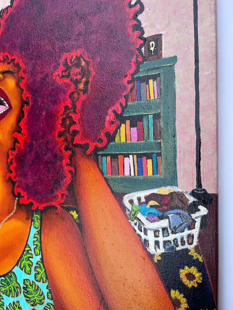 May include: A painting of a woman with a large, curly, red afro. She is wearing a blue and green tank top with a leafy pattern. The woman is sitting on a bed with a white laundry basket filled with clothes. A bookshelf with books is in the background.
