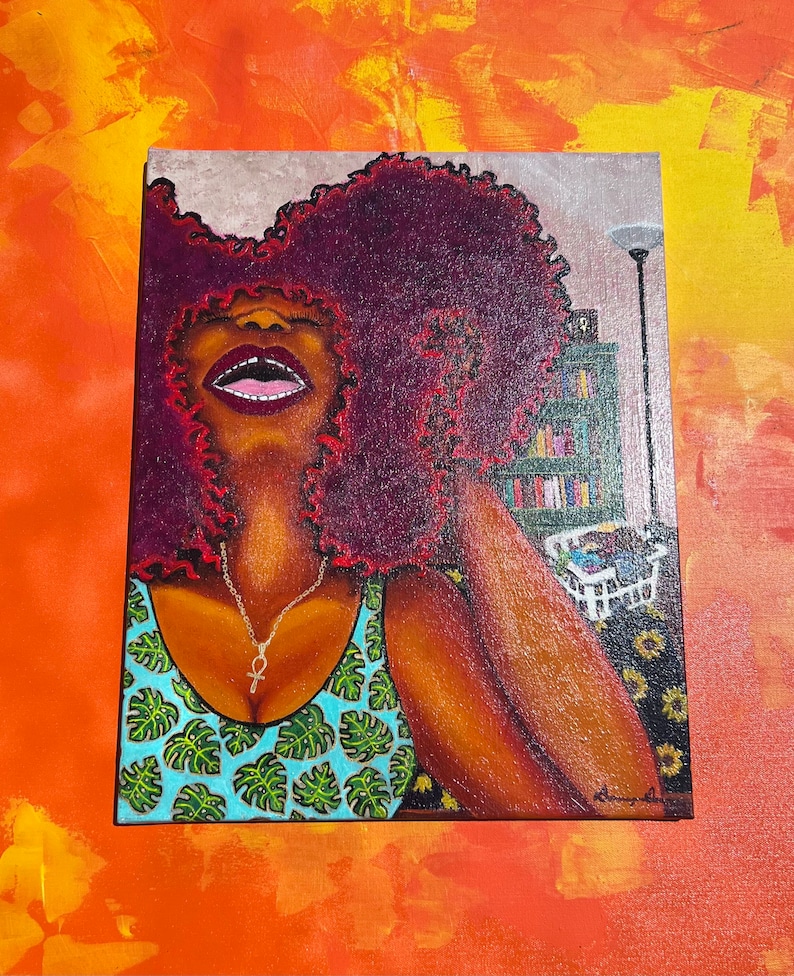 May include: A painting of a woman with large, curly, red hair wearing a blue tank top with a green tropical leaf pattern. She is wearing a silver necklace with an ankh pendant. The background is a blurry image of a bookshelf and a lamp.