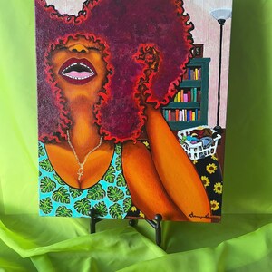 May include: A painting of a woman with a large, curly, red afro. She is wearing a green and blue tank top with a silver necklace. The background is a room with a bookshelf and a lamp.