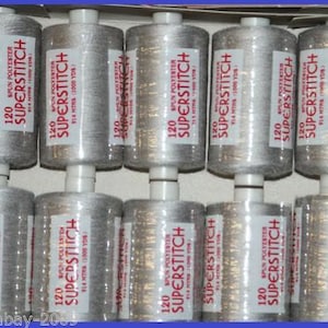 May include: A close-up of ten spools of silver thread, each labeled "120 SPUN POLYESTER SUPERSTITCH 914 MTRS (1000 YDS)".