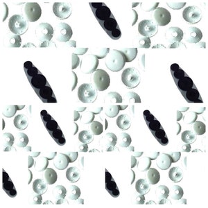 May include: A close-up of a collection of white plastic buttons with a raised center. The buttons are arranged in a grid pattern on a white background. There are also several black, oval-shaped objects with a series of bumps on them.