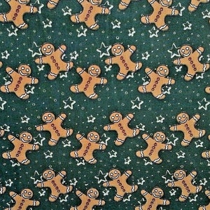 May include: A green fabric with a repeating pattern of gingerbread men and white stars. The gingerbread men are brown with white icing and red buttons.