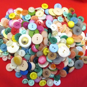 Peut inclure: Une grande collection de boutons en plastique colorés de formes et de tailles variées. Les boutons sont un mélange de couleurs unies et de motifs.