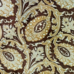 May include: Brown fabric with a white paisley pattern. The pattern is intricate and features a variety of floral and geometric shapes.