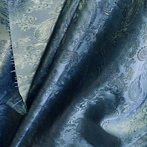 May include: Close-up of a dark blue fabric with a paisley pattern. The fabric has a subtle sheen and a textured surface.