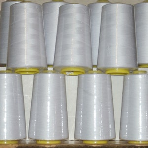 May include: A stack of white thread spools with yellow caps. The spools are arranged in a pyramid shape.