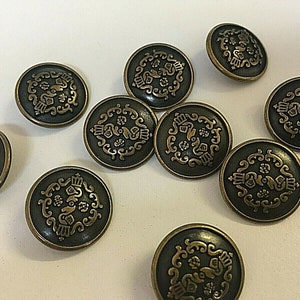 Könnte beinhalten: Sortiment von zehn runden, bronzefarbenen Knöpfen mit komplizierten, goldfarbenen Designs. Die Knöpfe haben eine erhabene, strukturierte Oberfläche.