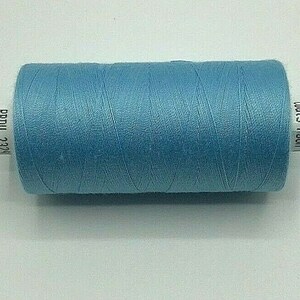 Könnte beinhalten: Eine Spule Coats 100% Baumwollgarn in hellblau. Die Spule ist mit "Coats 100%" und "2323U 480Y" beschriftet.