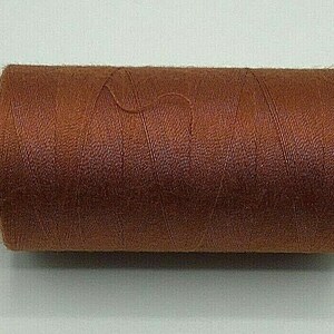 May include: A spool of brown thread with white labels at each end. The labels have the text "100" and "Coal" printed on them.