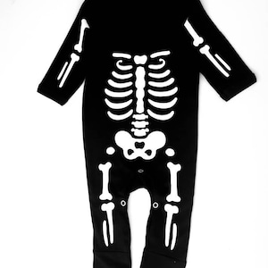 May include: Black long-sleeved baby onesie with a white skeleton design printed on the front.