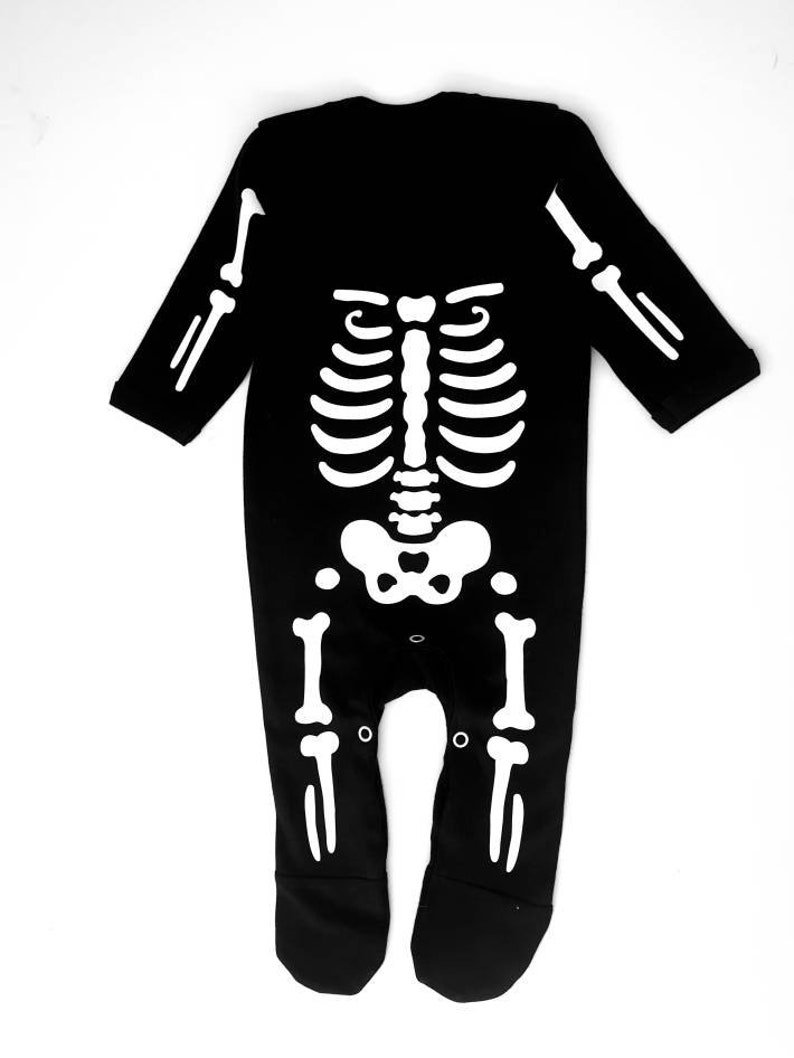 May include: Black long-sleeved baby onesie with a white skeleton design printed on the front.