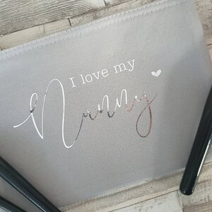 May include: A grey canvas makeup bag with a zip closure. The bag has the text "I love my mummy" printed on it in silver foil lettering.