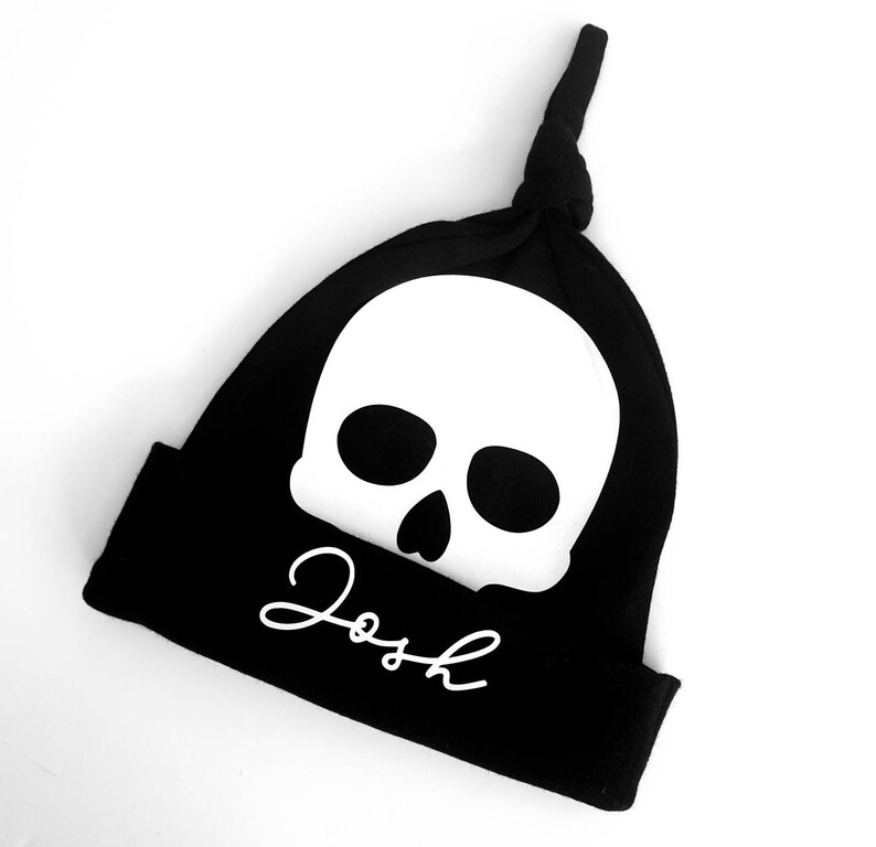 May include: Black knit beanie with a white skull and the name "Josh" written in white cursive.