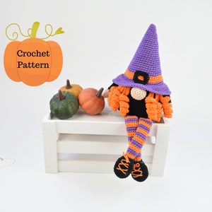 May include: Crocheted Halloween witch gnome with purple hat, orange and black striped legs, and orange hair. The gnome is sitting on a white wooden crate with three small pumpkins in front of it.
